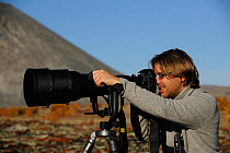 Laurent Joffrion looking through camera with long lens, Forollhogna National Park, Norway, September 2008