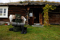 Rucksack and walking boots for camping expedition outside wooden building with grass roof, Forollhogna National Park, Norway, September 2008