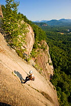 A woman rappels from the top of Cathedral Ledge.  Echo Lake State Park, White Mountains, in North Conway, New Hampshire, USA. October 2009