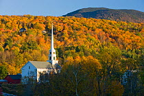 A church with its steeple rising above the autumnal / fall forest foliage. Stowe, Vermont, USA. October 2009