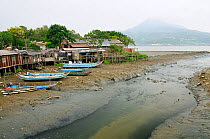 Dilapidated stilt houses and sampan style fishing boats on a tidal creek in the Danshuei river estuary, Danshuei / Danshui Taiwan. September 2009