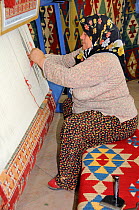 Woman weaving carpet by hand, Bergama, Turkey. August 2009