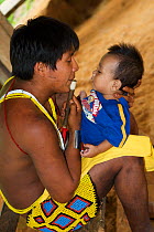 A young Embra Indian father holds his son while playing the flute, Soberania NP, rainforest, Panama, November 2008