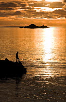 Man standing on the Old Quay, St. Martin's, with the island of Guthers behind. Isles of Scilly, January 2010.