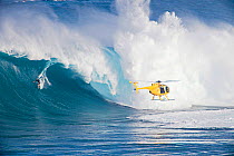 Helicopter filming a tow-in surfer at Peahi (Jaws) off Maui, Hawaii. Model released.