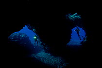 Divers at entrance to Second Cathedral off the Island of Lanai, Hawaii. Model released.