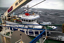 Fishing vessel "Ocean Harvest" seen from aboard pair trawler, manouvering alongside to pass over trawl net. North Sea, February 2010, Property released.