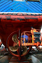 Engineers carrying out hull repairs on a fishing vessel in dry dock, Skagen, Denmark. March 2010.