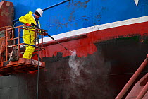 Algae being pressure washed from a fishing vessel's hull in dry dock, Skagen, Denmark. March 2010.