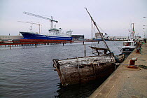 Old and the new. Newbuild in background and old sunken sailboat in foreground. Skagen harbour, Denmark, March 2010.