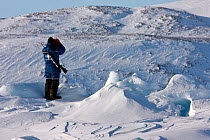 Local hunter armed  with rifle scouting for Polar Bear ( Ursus Maritimus) Ittoqqortoormiit,  Scoresbysund, North East Greenland. March 2009.