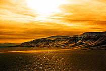 Sun setting over mountains in Jameson Land, North East Greenland. February 2009.