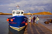 People queuing for the Passenger Ferry "Voyager of St. Martin's" arriving at Lower Town Quay in the early morning. St. Martin's, Isles of Scilly, UK