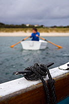Man rowing a tender towards the beach from a boat off St. Martin's, Isles of Scilly, UK. Model Released