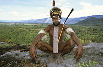 Portrait of Dani man, sitting with painted face, head-dress, nose adornment made of bone, and penis case, Baliem valley, West Papua, former Irian-Jaya, Indonesia, August 2002 (West Papua).