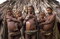 Group of Yali women in traditional dress, holding children in their arms in front of hut. West Papua, former Irian-Jaya, Indonesia, August 2002 (West Papua).