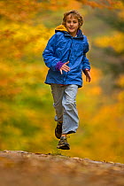 Boy, aged 12, running in autumn woodland, upstate New York,  USA, model released