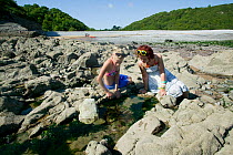 Twelve-year and sixteen-year  girls looking in rockpools, Pwll Du National Trust coastal property Gower West Glamorgan, Wales, August 2009