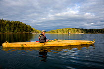 Kayaker in a bydarka style boats exploring the waters of Wescott Bay San Juan Island. Washington, USA, May 2009, model released