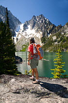 Hiker at Colchuck Lake in the Alpine Lakes Wilderness. Washington, USA, July 2009, model released