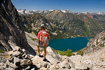 Hiker on the trail to Aasgard Pass with Colchuck Lake seen below, Alpine Lakes Wilderness. Washington, USA, July 2009, model released