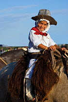 A young gaucho (cowboy), dressed in traditional costume, rides a horse (Equus caballus) during the Fiesta De La Patria Gaucha, Tacuarembo, Uruguay, April 2008