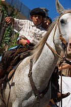 Two young gauchos (cowboys) ride a horse (Equus caballus) during the parade of the Fiesta De La Patria Gaucha, Tacuarembo, Uruguay, April 2008