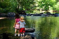 Young brother and sister playing in the Eightmile River in the Nature Conservancy's Pleasant Valley Preserve. Lyme, Connecticut, USA, August 2006. Model released.
