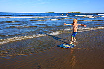 Young boy skim boarding at Popham Beach State Park in Phippsburg, Maine, USA, July 2009. Model released.