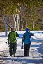 Couple carrying cross-country skis at Medawisla Wilderness Camps near Greenville, Maine, USA, March 2009.