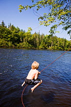 Boy playing on rope swing over the Androscoggin River, Mollidgewock State Park in Errol, New Hampshire, USA, August 2008. Model released.