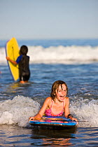 Young girl boogie boarding at Hampton Beach, New Hampshire, USA, August 2008. Model released.