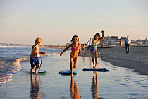 Children playing with boogie boards on Hampton Beach, New Hampshire, USA, August 2008. Model released.