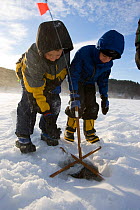 Two young brothers ice fishing on the West River in Brattleboro, Vermont, USA, February 2007. Model released.