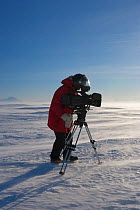 Cameraman with camera and tripod filming,  Ross Sea, Antarctica. November 2008