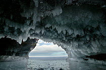 Ice hanging from arch in sea cave carved in soft sandstone cliffs, frozen lake, Squaw Bay, Lake Superior, Apostle Islands National Lakeshore, Wisconsin, USA, February 2009