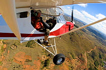 Photographer taking photos from small plane, Tana, Madagascar. November 2008