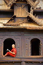 Buddhist monk reading inside teakwood monastery. Bagan, Mandalay State, Myanmar (Burma).September 2009