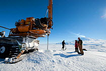 Crew watch heavy machinery drilling through the ice to create an ice-hole for BBC filming crew, McMurdo Sound, Ross Sea, Antarctica, November 2008