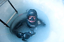 Camerman Doug Allan at frozen water surface of drilled ice hole, BBC film crew, McMurdo Sound, Ross Sea, Antarctica, November 2008