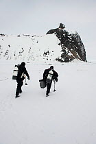 Doug Allan, BBC cameraman and another, walking across ice to reach ice-hole for underwater filming, McMurdo Sound, Ross Sea, Antarctica, November 2008