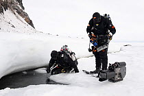 Doug Allan, BBC cameraman and another, preparing to enter ice-hole for underwater filming, McMurdo Sound, Ross Sea, Antarctica, November 2008