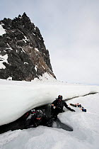Doug Allan, BBC cameraman and another, entering ice-hole for underwater filming, McMurdo Sound, Ross Sea, Antarctica, November 2008