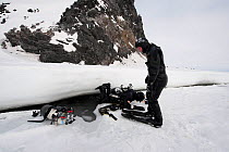 Doug Allan, BBC cameraman and another, preparing to enter ice-hole for underwater filming, McMurdo Sound, Ross Sea, Antarctica, November 2008