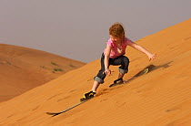Mimi Widstrand sand boarding down a sand dune, Dubai, United Arab Emirates, February 2007. Model released