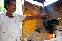 Colombian woman cooking over a Bindi, a clay pot used to increase wood burning efficiency by reducing amount of wood burned. Los Limites, Colombia, South America. February 2008
