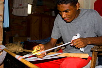 Colombian man cutting strips of recycled plastic bags to be woven into products.This project has recycled more than 1.5 million plastic bags and provides an income to the village living around the for...