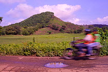 Motorcycle whizzes past pasture and half-denuded hill (once Cotton-top tamarin habitat). Colombia, South America