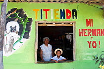 "Titienda" shop - owner with grandson tending their small grocery store in Los Limites, Colombia. Advertising the presence of the cotton-top tamarin in their forests helps educate the community and is...