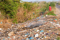 Children walking through roadside trash in Colombia, South America. February 2008